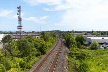 Fototapeta na wymiar Railroad tracks - greenery - industrial area - tower - blue sky