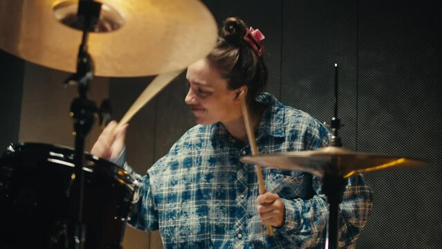Expressive drummer young woman playing on dums in studio room close-up. Rock metall music artist 