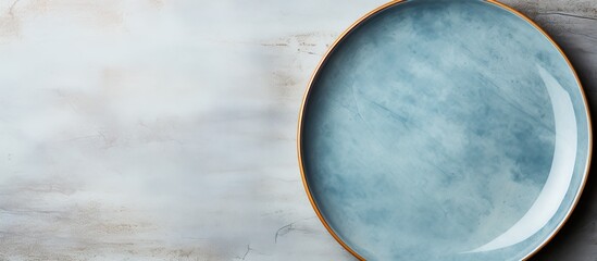 A vintage ceramic plate colored blue and empty rests on a surface made of beige marble