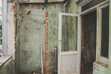 Old, dirty doors with windows and a shabby green wall in an old abandoned house.