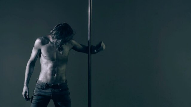 Pole dancer. Guy does gymnastic exercises on pole dance. Pole dancing for slim fitness body. Flexibility. Pole dance. Pylon dancing strength, flexibility, and grace. Strip muscular man dancer.