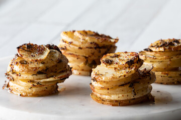 Homemade seasoned potato stacks on a marble slab, ready for eating.