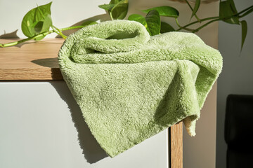 Soft plush green cleaning cloth on a white dresser in a home environment.