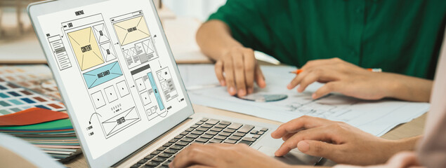 Cropped image of interior designer team discuss the material color while laptop displayed website wireframe designs for mobiles app and website. Creative design and business concept. Variegated.
