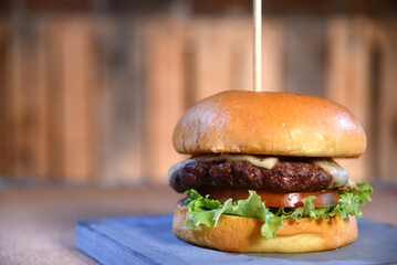 beef burger with sandwich bun salad onion and cheese fast food isolated on wooden table image