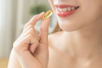Fotobehang Dietary supplement, pretty asian young woman, girl hand holding medical pill capsule, take or eat vitamin fish oil for treatment for skin, hair and nail strengthener near window at home, healthcare. © KMPZZZ