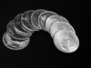 closeup shot of fresh new indian 2 (two) rupee silver coins arranged in a snake like curve in a black background