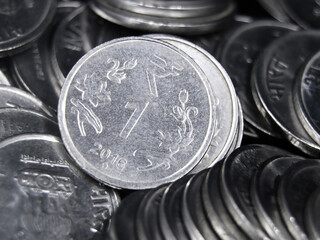closeup shot of indian one rupee shiny silver coins in a messy mixed up pile 