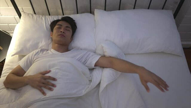 Young Asian man lying on the bed Use his hand to fumble his wife who thinks her woke up together that morning.