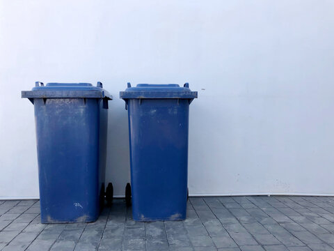 Blue garbage bin, trash bins near house wall.