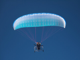 Motor paraglider on clear blue sky background