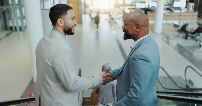 Happy businessman, handshake and meeting on escalator for partnership, b2b or deal at airport. Business people shaking hands with smile for travel, teamwork or agreement together on moving staircase