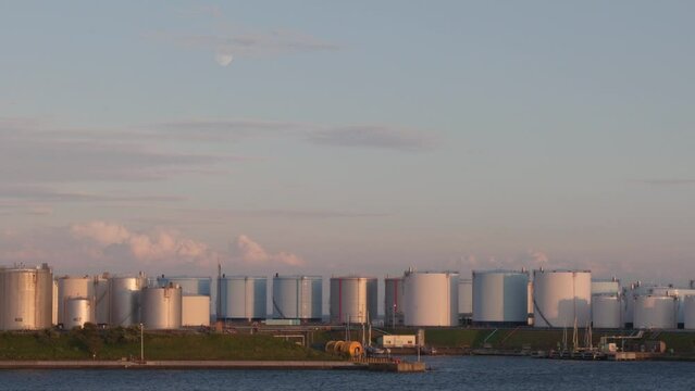 Large LNG storage tanks at port facility at sunset, handheld