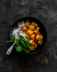 Simple vegetarian lunch - spicy baked pumpkin, rice and spinach on a dark background, top view