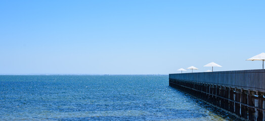 A pier stretching into the blue horizon