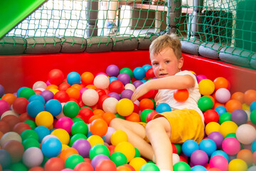 Boy playing on the playground, in the children's maze with balls.