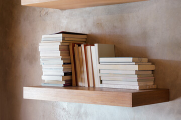 Stack of books on floating wooden bookshelf. Education and knowledge concept. Pile of books to...