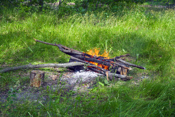 View of the burning campfire in the camp. Campfire in the green grass