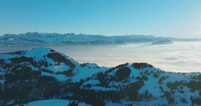 Aerial drone fly above the clouds over summit of Mount Rigi (Rigi Kulm) and Lake Lucerne underneath, Switzerland. Amazing snow and fog covered Swiss alps mountain peaks and winter scenery landscape.