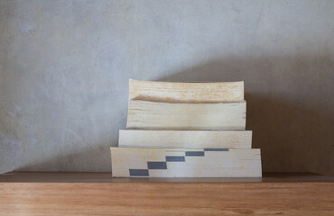 Stack of yellowish and vintage books on floating wooden bookshelf. Education and knowledge concept. Pile of books to read