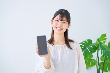 Fototapeta premium スマートフォンの画面を見せる若い女性