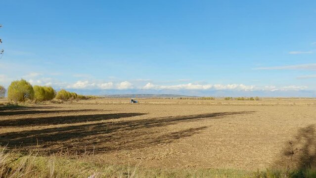 Small figure of a tractor working in the field.
Agricultural landscape with tractors and mountains in background
