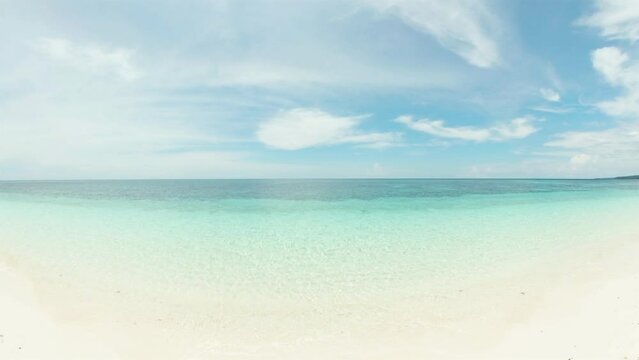 Turquoise ocean water and waves over sandy beach in Mantigue Island. Camiguin, Philippines.