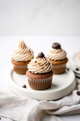 three chocolate cupcakes with chips and caramel on a plate