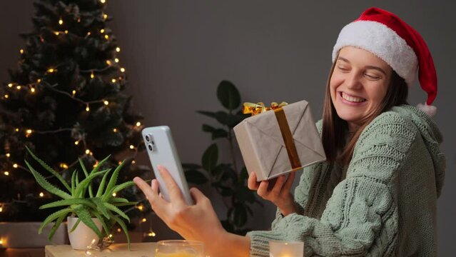Attractive pretty cheerful woman holding in hand giftbox making selfie having fun blogging in decorated house blogger taking photo for social network wearing festive clothing.