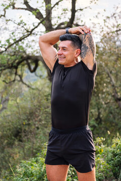 vertical photo of a man stretching and warming up arms for sports in the countryside, concept of sport in nature and active lifestyle