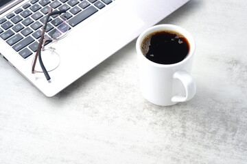 コーヒーを飲みながらノートパソコンでデスクワーク中のイメージ	

