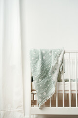 Muslin baby blanket hanging on child's bed in nursing room