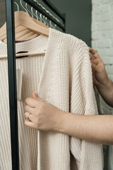 The choice of clothes, the girl's hand in choosing a dress, an outfit on a hanger in the wardrobe in the room, a closet at home. Wardrobe in the house. Clothes for women. Bags. Clothing store.