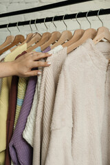 The choice of clothes, the girl's hand in choosing a dress, an outfit on a hanger in the wardrobe in the room, a closet at home. Wardrobe in the house. Clothes for women. Bags. Clothing store.