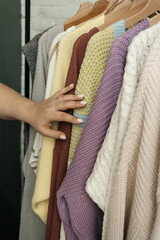 The choice of clothes, the girl's hand in choosing a dress, an outfit on a hanger in the wardrobe in the room, a closet at home. Wardrobe in the house. Clothes for women. Bags. Clothing store.