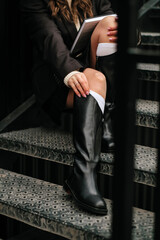 Black high boots on women's feet. Women's legs close-up. A woman in flesh-colored tights and black boots.