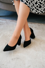 Black high-heeled shoes. Women's legs close-up. A woman in flesh-colored tights and black high-heeled shoes.