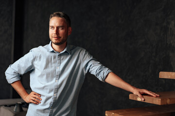 Confident young businessman standing near wooden ladder portrait