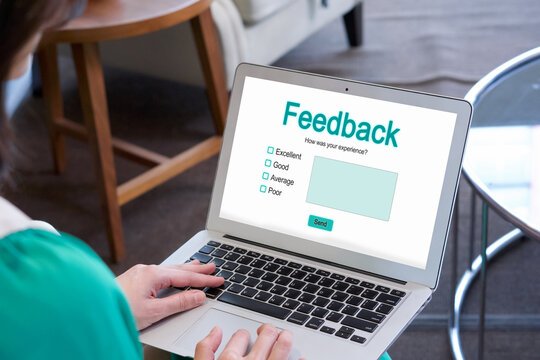 A lady is busy typing on her laptop computer which shows a feedback form on its screen.