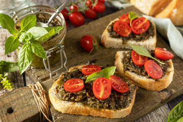 Homemade bruschetta with pesto sauce, fresh tomatoes on a wood background. Traditional italian appetizer or snack, antipasto.