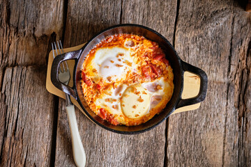 Shakshuka. Scrambled eggs with tomatoes, bell peppers, chili peppers, herbs.