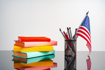 USA flag with pile of colorful books on black table