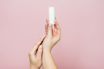 Hand holding white bottle. Drops for eye, nose or ear in hand on pink background. Pharmaceutical product.
