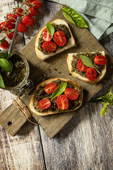 Homemade bruschetta with pesto sauce, fresh tomatoes on a wood background. Traditional italian appetizer or snack, antipasto. View from above. Copy space.