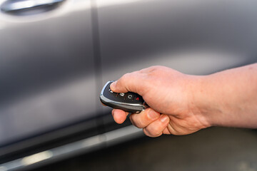 Man opening his car door with the control remote key. Car remote control by smart key. - obrazy, fototapety, plakaty