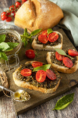Traditional italian appetizer or snack, antipasto. Homemade bruschetta with pesto sauce, fresh tomatoes on a wood background.