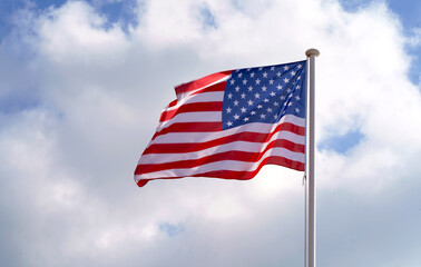Large American flag waving on flag pole with cloud blue sky. Windy and sunny day with waving stars...