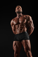 Fototapeta na wymiar Handsome strong athletic men pumping up muscles. Workout, bodybuilding concept. Black background.