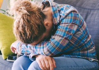 Portrait of sad upset adult woman female sitting on sofa embrace knees lost in bad pessimistic thoughts suffer alone. Stressed adult people feel lonely desperate has broken heart. Female life problems