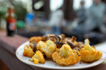Cauliflower and mushrooms fried in spices on the grill